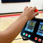 **

A person performing a "Bleep Test" (shuttle run) in a school gymnasium. Focus on the cardiovascular exertion and the effort being put into the activity. Include a timer or display showing the level of the test to indicate intensity.

**